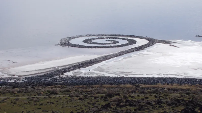 Obra monumental de land art en espiral junto a un lago salino en un paisaje remoto